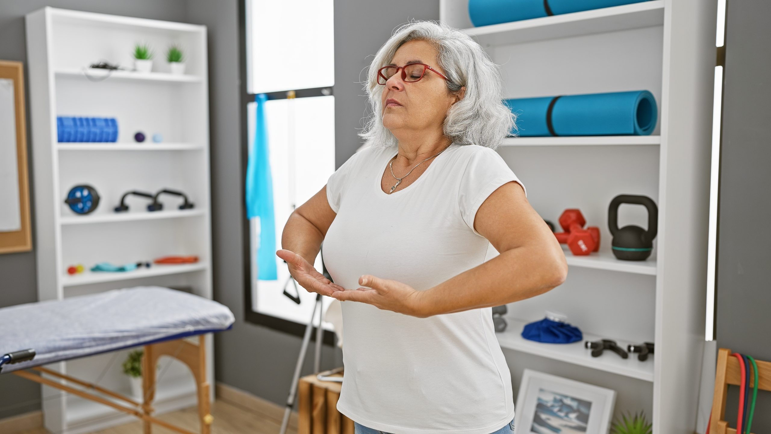 A,mature,woman,meditates,in,a,modern,rehab,clinic,,surrounded